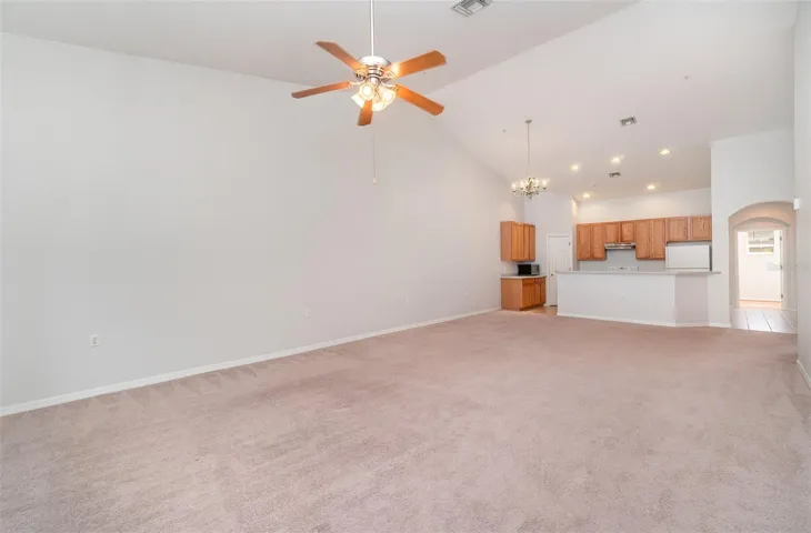 A view from the balcony end presents the living room, dining area, and kitchen in one sweeping glance. Positioned to the right, one can find the entrance to the primary bedroom.