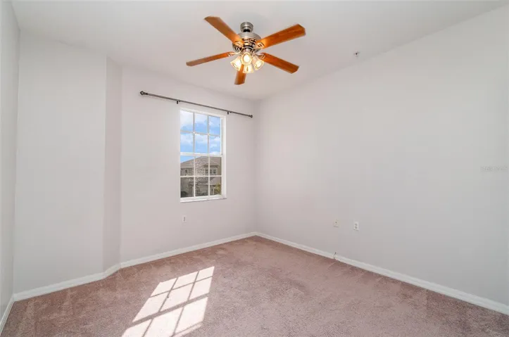 A well-lit guest bedroom equipped with a Ceiling fan and Wide closet.