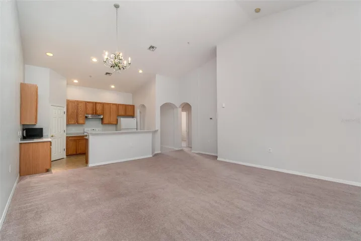 A generously sized living area, highlighted by its lofty ceilings, flows openly into the dining space and kitchen. To the right, and extending down the hallway, lies the entrance to the cozy den.