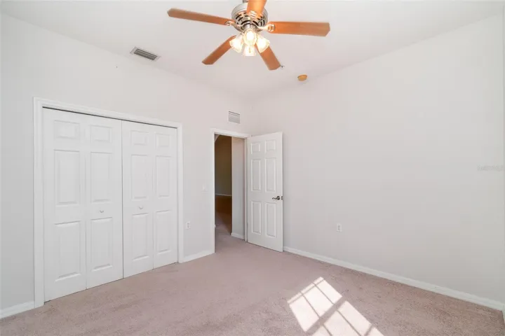 A well-lit guest bedroom equipped with a Ceiling fan and Wide closet.