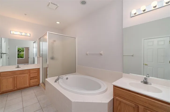 The Primary bathroom features two separate vanities with sinks, a generously sized soaking tub, and a spacious walk-in shower. Access to the private commode and walk-in closet from here.