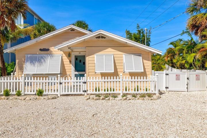 Front of home with Bahama shutters, picket fence