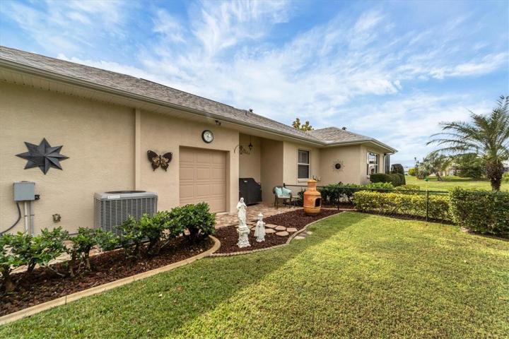Opposite side of back of home from pool and open patio is a fenced area.  Notice recessed space perfect for bbq and smaller overhead door from oversized garage for each of moving things in and out as well as possibly storing the lawnmower