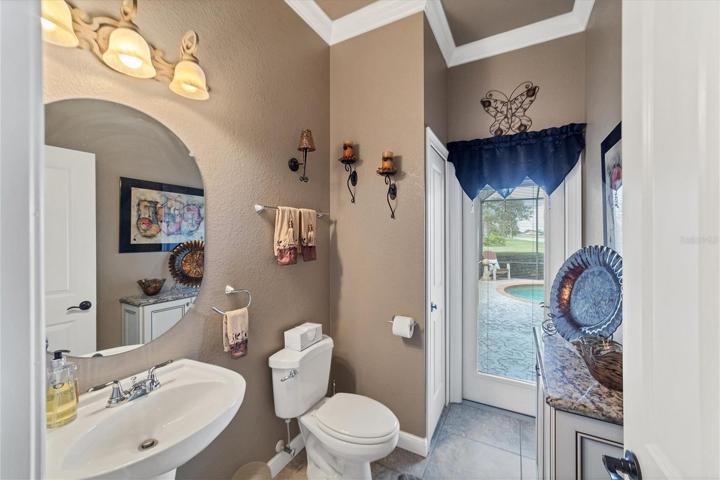 HALF bath with french door access to pool, no need to walk through house with wet bathing suits! Pedastal sink, linen closet and built in cabinet on right