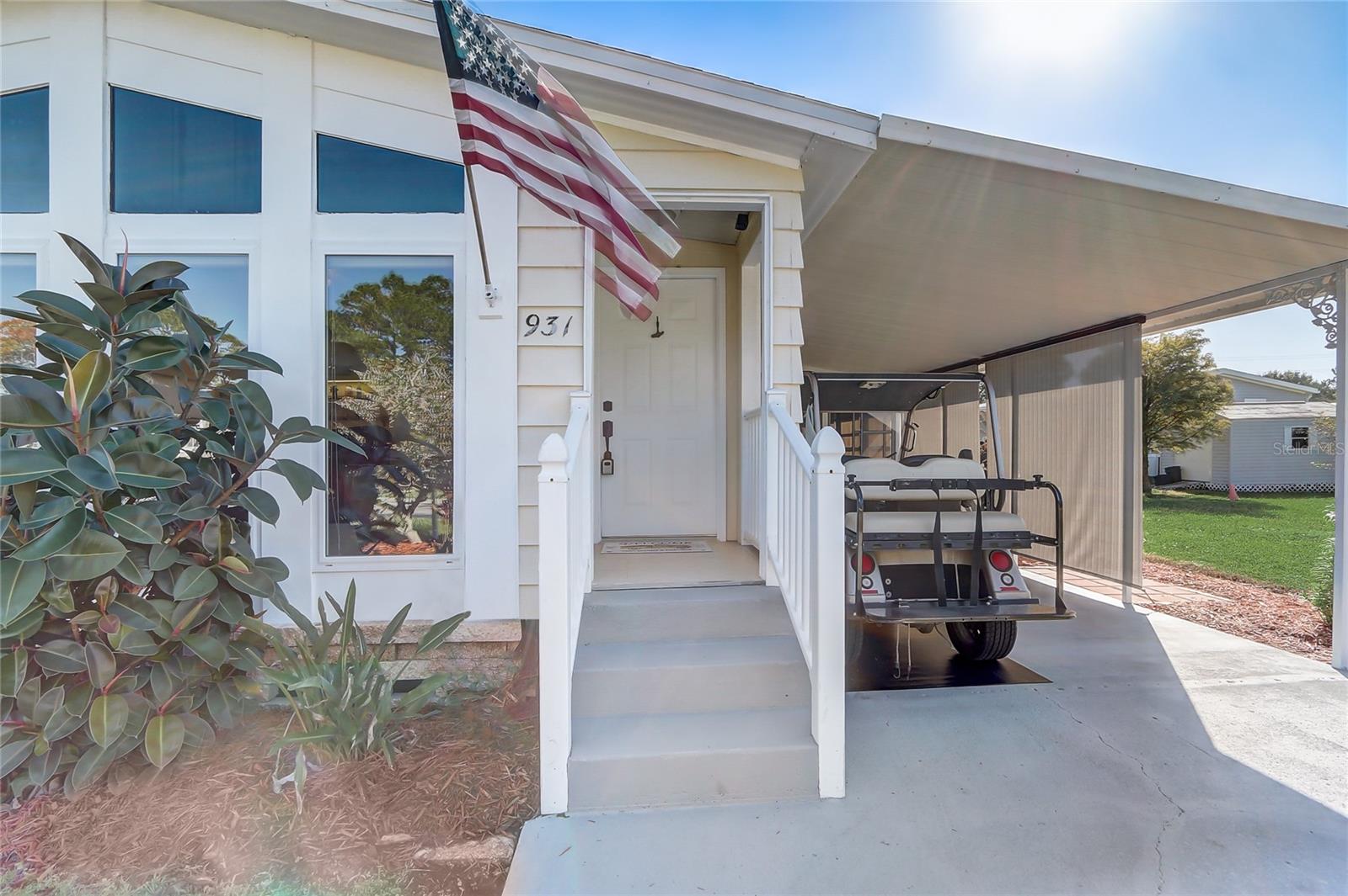 Covered entry with white vinyl handrails and steel entry door