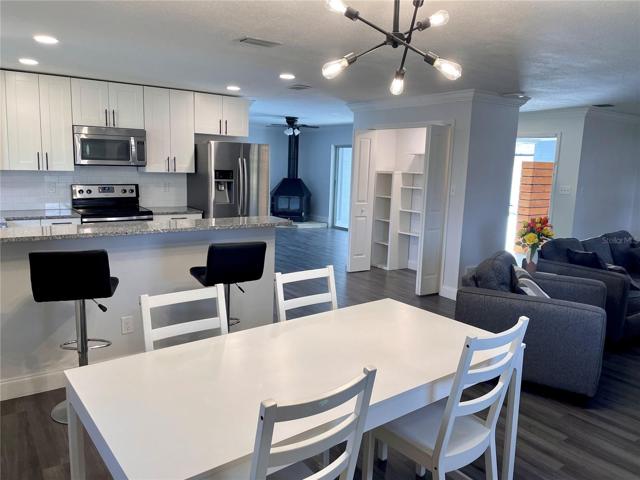 View of the kitchen, and main living room as seen from the dining room, with the main entry door to the home in the far back right