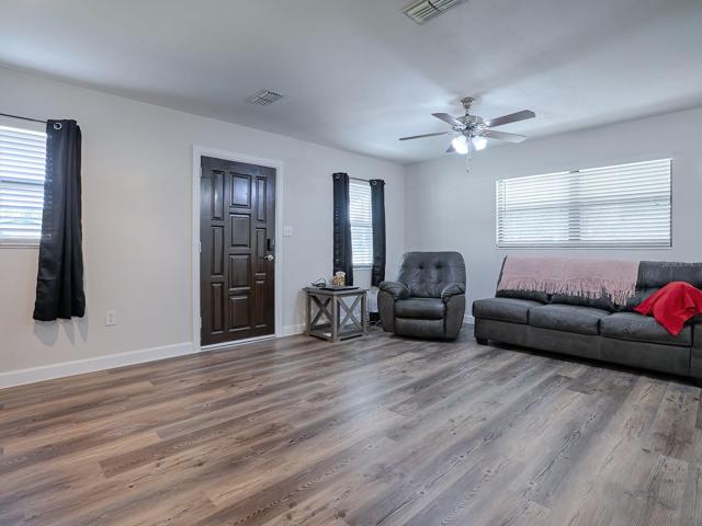 Spacious Living Room featuring new paint, Luxury Vinyl Plank Flooring, Moulding and beautiful solid wood, vintage entry door.