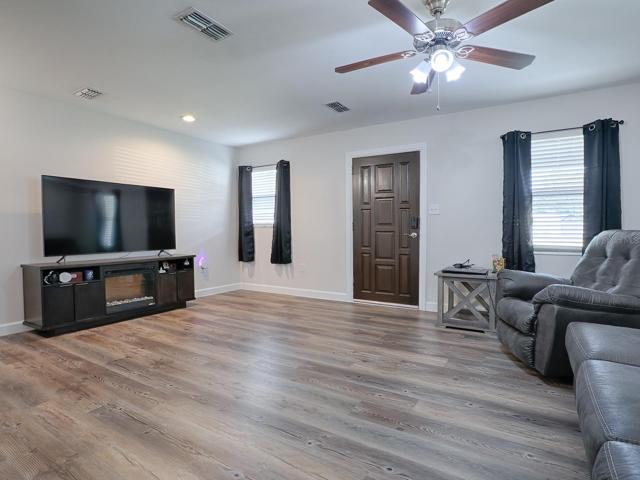 Spacious Living Room featuring new paint, Luxury Vinyl Plank Flooring, Moulding and beautiful solid wood, vintage entry door.