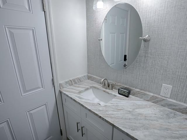 Bathroom featuring new custom White Shaker Cabinets, Granite Countertop, Paint & Wallpaper and Lighting Fixture.