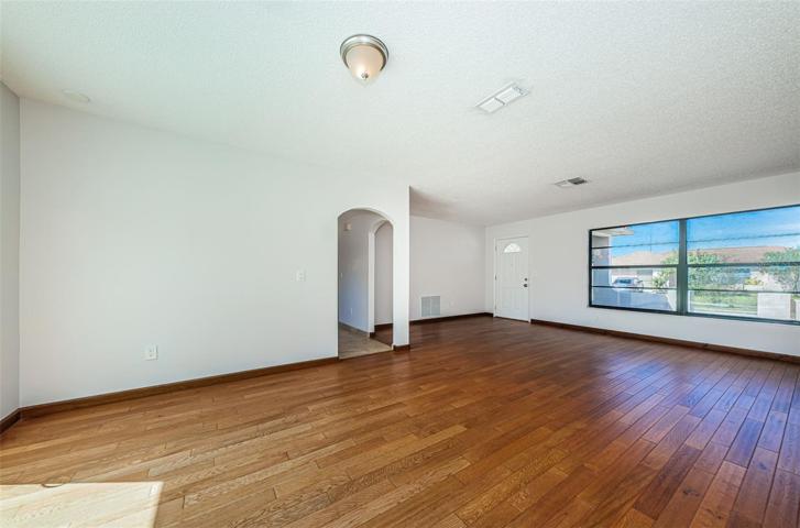 View of living room from back left corner, looking toward front door. Arches are to breakfast nook and kitchen