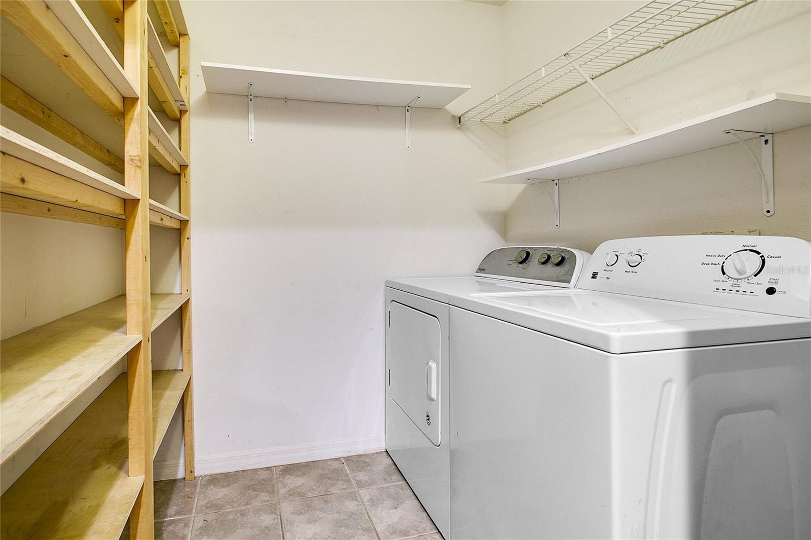 Laundry room off of kitchen includes washer and dryer along with custom built-in pantry shelves.
