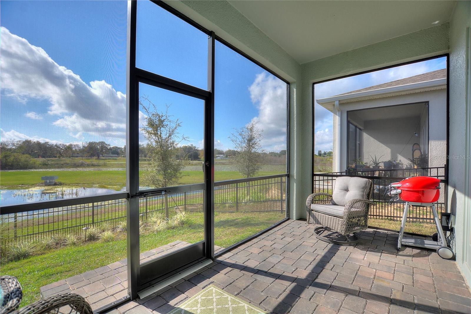 Screened patio overlooks fenced yard and pond.