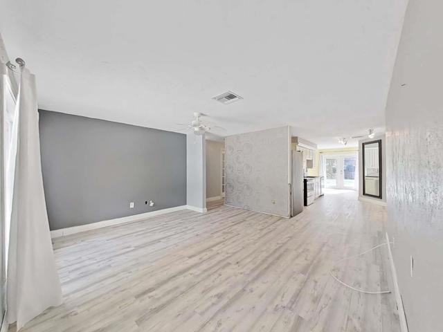 Living room leading to the front two bedrooms and kitchen. Beautiful light shining through the french doors leading the pool area.