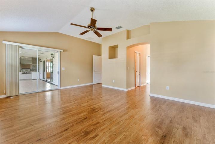 PRIMARY BEDROOM - View shows SLIDING GLASS DOORS to ENCLOSED LANAI (L) & hallway to ENSUITE BATHROOM