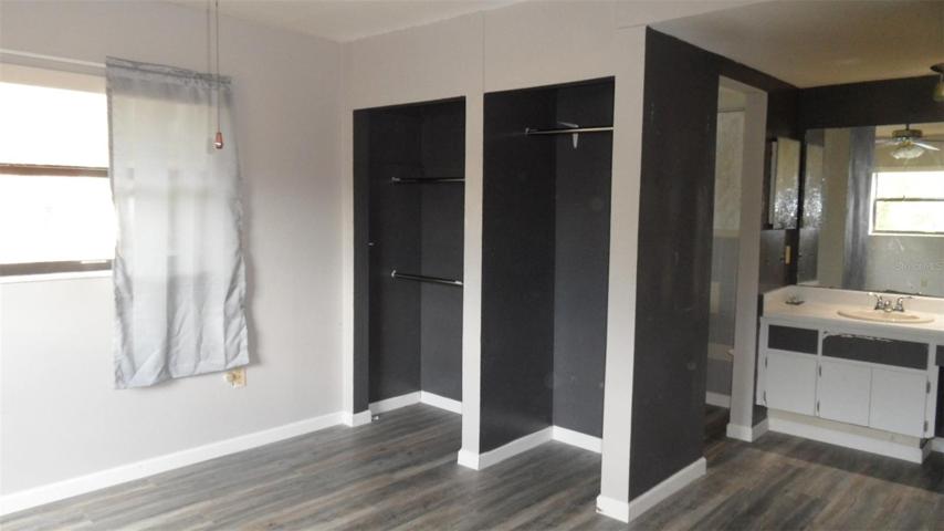 Primary bedroom with closets en suite bathroom with sink/vanity area and shower & commode area separate through doorway