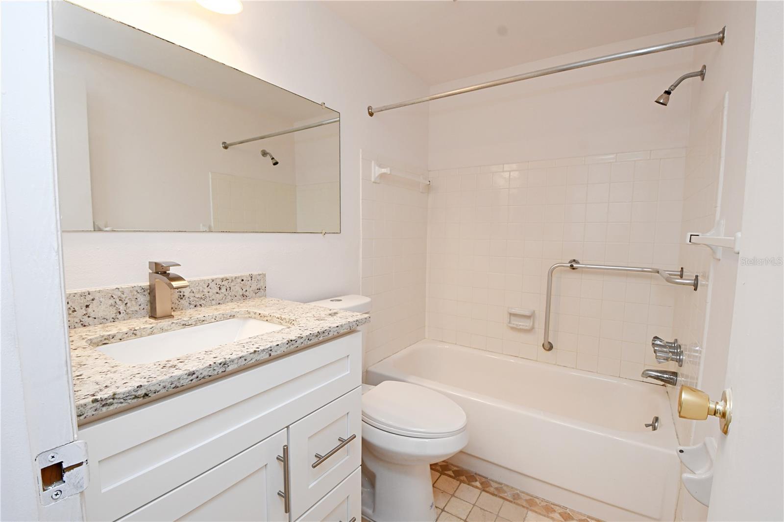 The bathroom has also received tasteful upgrades, including a new vanity and toilet. For added convenience, a handrail has been installed in the bathtub, ensuring comfort and accessibility.