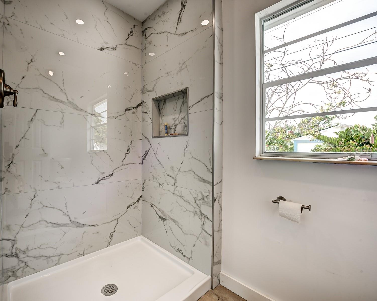 The ensuite primary bath features gorgeous porcelain tiled walls in the shower, a shampoo niche and a window for natural light.