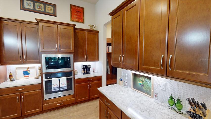 Experience a touch of elegance in the heart of your kitchen with cabinetry adorned in exquisite crown molding, delicately illuminated by enchanting downlighting. The captivating beauty is further enhanced by a decorative backsplash, adding a subtle yet striking visual texture that complements your culinary haven