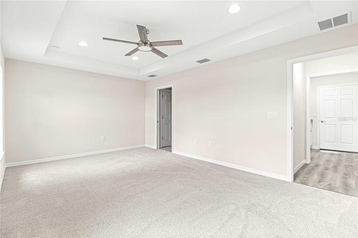 Owners suite with extra lighting tray ceilings and ceiling fan