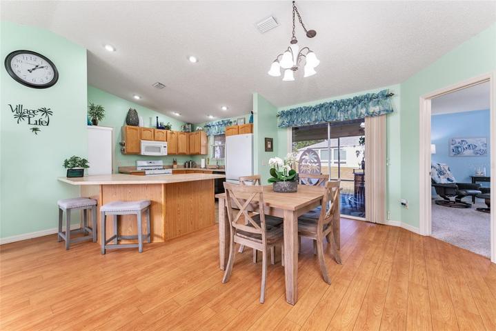 View of KITCHEN (L), DINING ROOM (Center), & Doorway to PRIMARY BEDROOM (R). Note: CATHEDRAL CEILING over main living area.