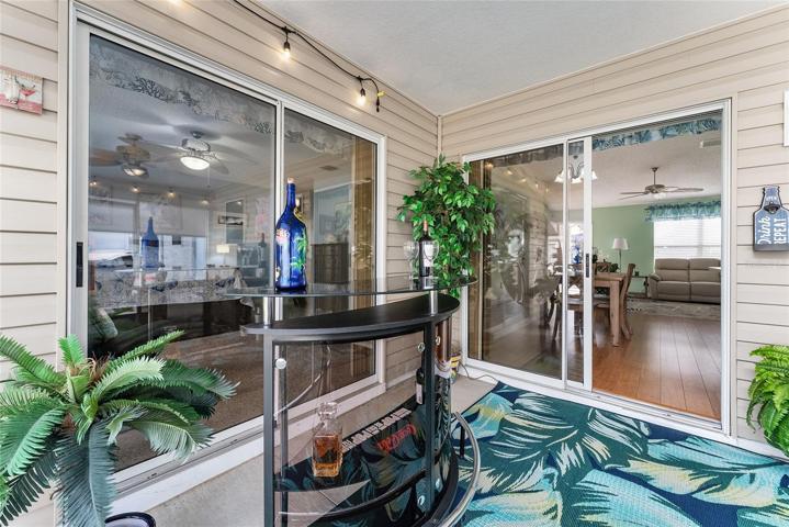 View of SCREEN ENCLOSED LANAI shows SLIDING GLASS DOORS to PRIMARY BEDROOM (L) and another set leading into the DINING ROOM. Note: DRY BAR is great for entertaining guests!