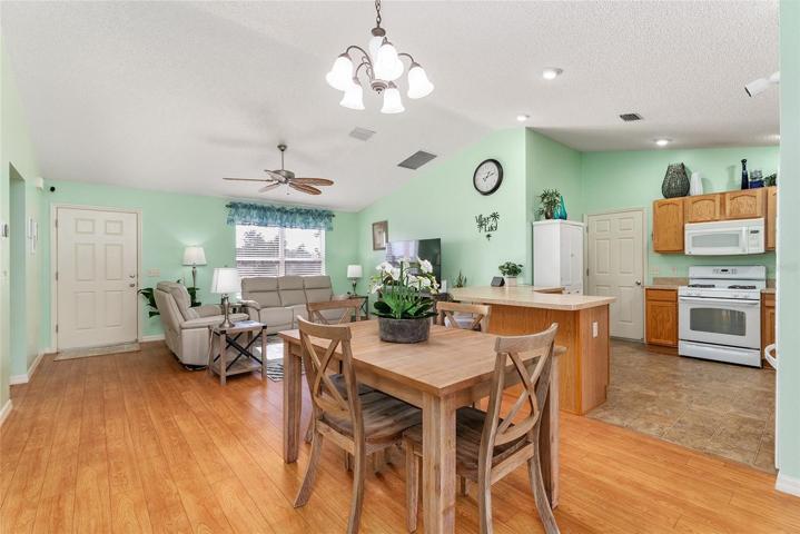 View of LIVING ROOM (back L), KITCHEN (back R) & DINING ROOM (front center). Note: Door in kitchen leads to garage.