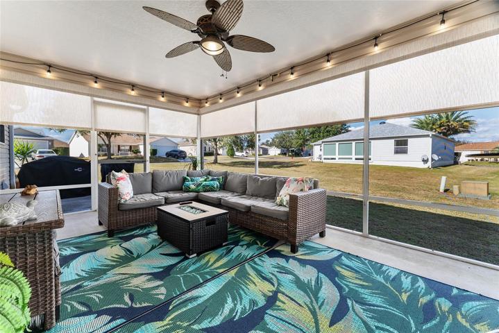 Colorful decor & festive lights in the SCREEN ENCLOSED LANAI with SOLAR SHADES! Note: Screen door leads to OPEN CONCRETE PATIO, perfect space for BBQ equipment!