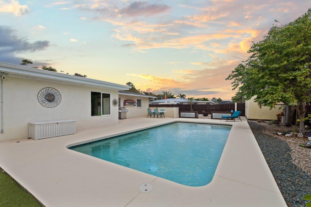 Back yard featuring a heated pool, extended lanai, fenced-in yard, 10'x20' shed, and artificial turf.
