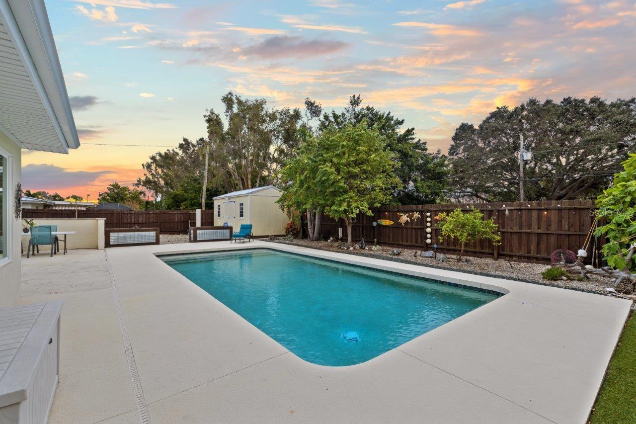 Back yard featuring a heated pool, extended lanai, fenced-in yard, 10'x20' shed, and artificial turf.