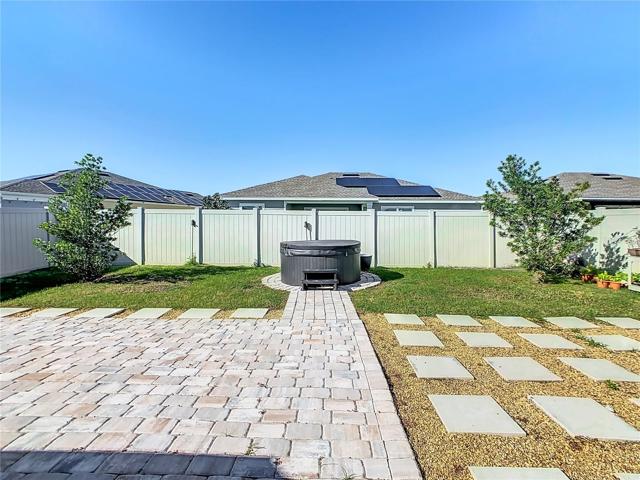 Exterior Area with Pavers, Grass, Stones, Steppers, Jacuzzi and Partial PVC Fence.