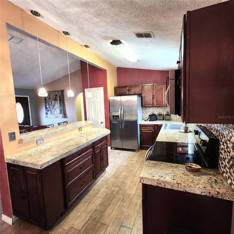 Kitchen with plenty of countertop space, closet pantry, SS appliances, double sink w/disposal, and pendant lighting