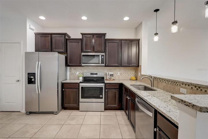 Kitchen with granite counters, stainless steel appliances and dark cabinets
