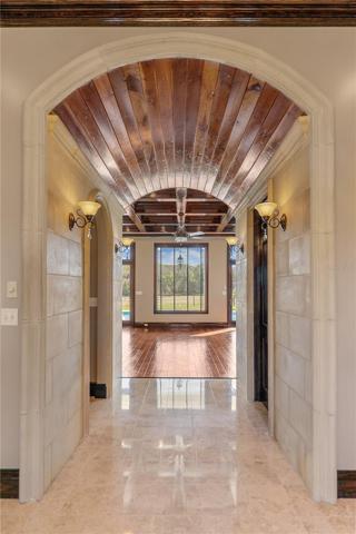Cast stone archway leading from foyer into living room, half bath, and primary bedroom