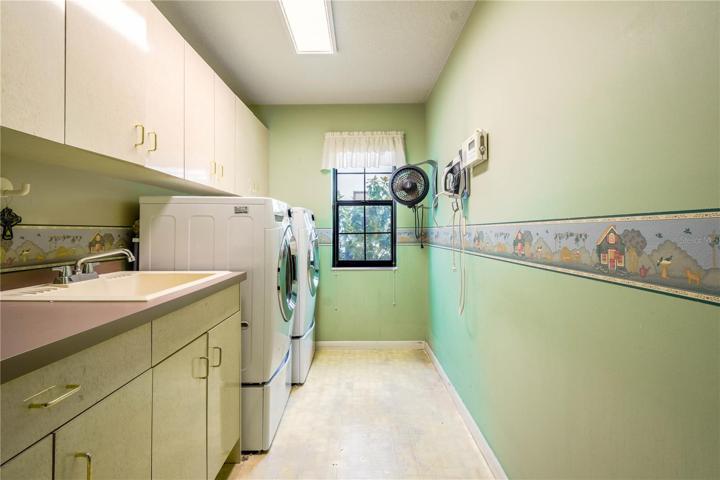 The spacious laundry room has a utility sink and plenty of cabinets for storage.