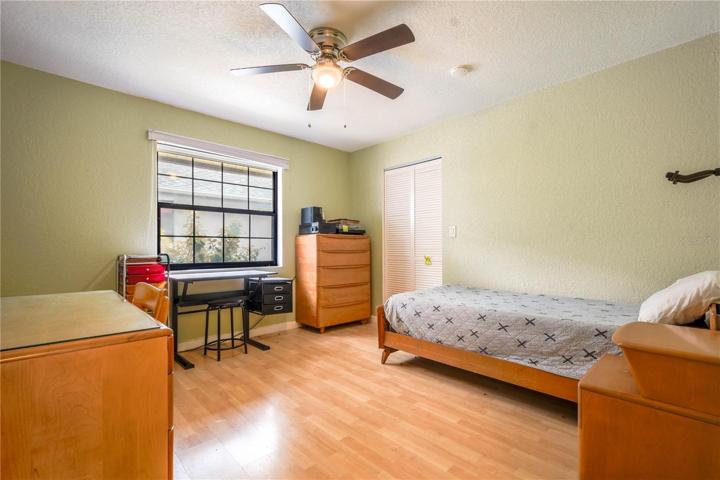 Bedroom 2 is light and bright with a walk in closet, wood laminate flooring and a ceiling fan.