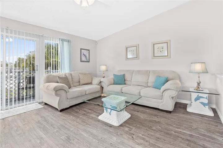 Spacious living area with vaulted ceilings and access to patio.