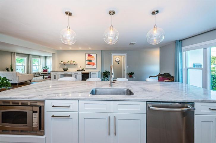 Oversized kitchen island discreetly hides appliances and provides a stunning space for socializing.