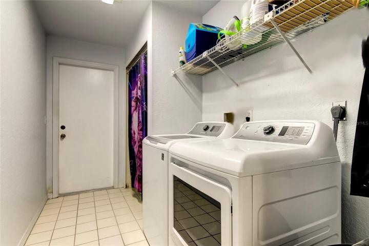 Laundry room connecting garage to kitchen with full closet and shelving.