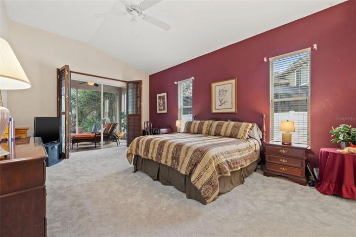 Primary Bedroom with new carpet, sliders, that open to the conservation area and garden, and plantation shutters to lanai