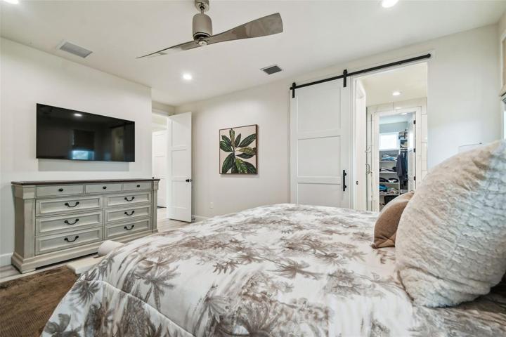 Spacious primary bedroom suite with sliding glass doors to lanai, barn door to bathroom suite and walk-in closet.