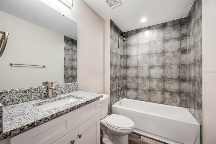 hallway bathroom close up, granite sink-top, tub/shower combo with tile walls