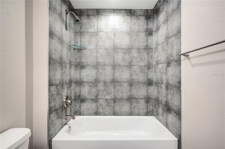 hallway bathroom shower/tub combo with tile walls