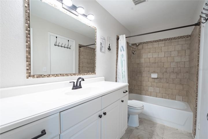 Bathroom 2 has a mirrored vanity with storage and a tub with shower.