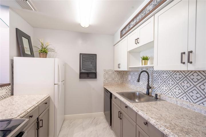 The kitchen features solid countertops and artistic tile backsplash.