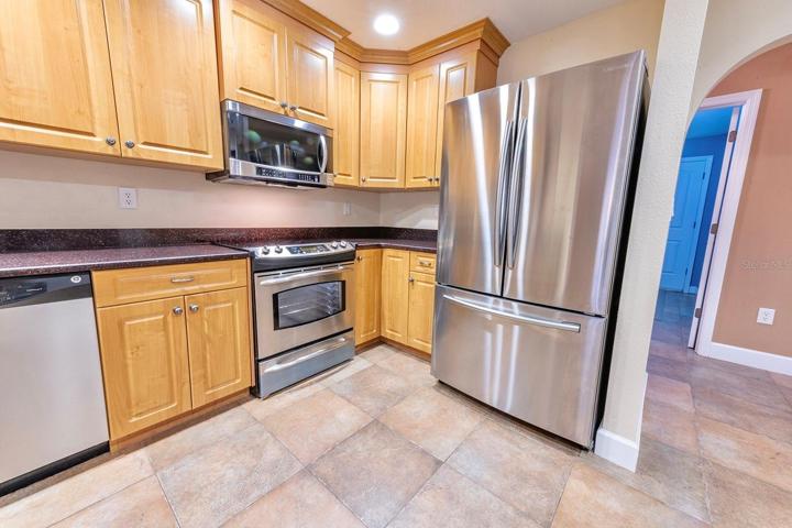 Grand kitchen! Granite, wood cabinets, stainless appliances, bar with extra cabinet storage, double door pantry and room for an island or dinette