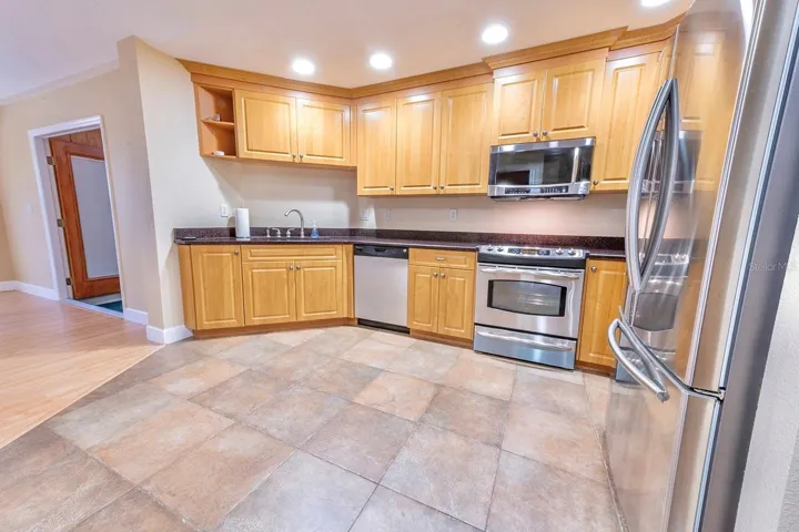 Grand kitchen! Granite, wood cabinets, stainless appliances, bar with extra cabinet storage, double door pantry and room for an island or dinette