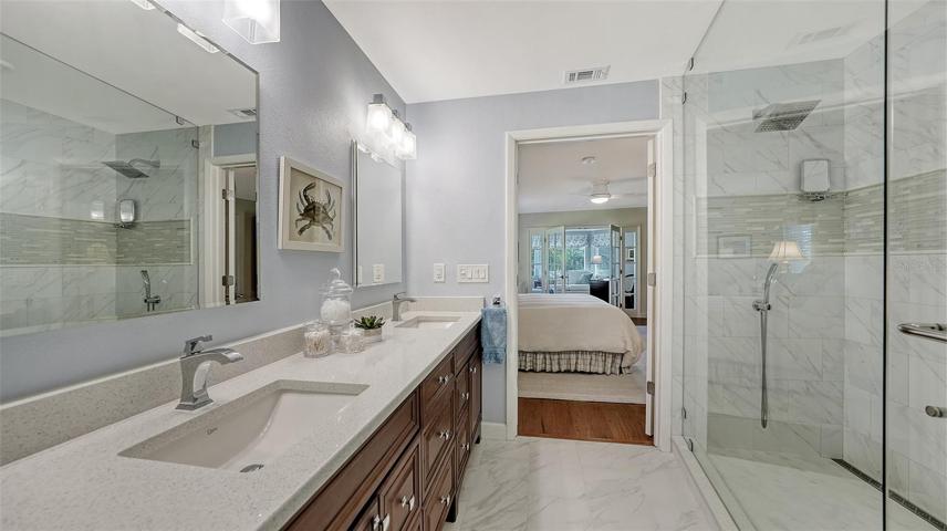 A large walk in shower w/ 2 showerheads & double vanities & custom mirrors w/ electric power