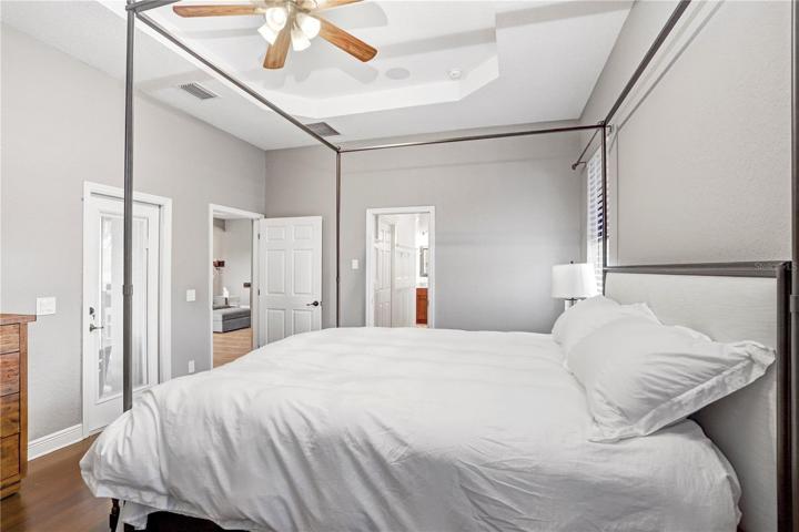 PRIMARY BEDROOM - DOOR ON LEFT LEADS TO THE COVERED/SCREENED-IN LANAI/POOL - DOOR IN THE CENTER LEADS TO 2 WALK-IN CLOSETS & PRIMARY BATH (GARDEN TUB,WALK-IN SHOWER, WC, DOUBLE VANITY