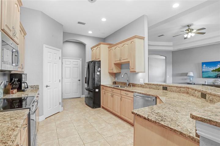 VIEW TO KITCHEN: BREAKFAST BAR, GRANITE COUNTERTOPS & PANTRY - DOOR TO THE CENTER LEADS TO THE GARAGE;