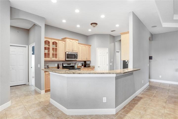 VIEW TO KITCHEN TAKEN FROM DINETTE: BREAKFAST BAR, GRANITE COUNTERTOPS & PANTRY - DOOR TO THE RIGHT LEADS TO LAUNDRY ROOM; ENTRANCE WAY ON THE LEFT LEADS TO BEDRROMS 1 & 2, SHARED BATH & POOL BATH